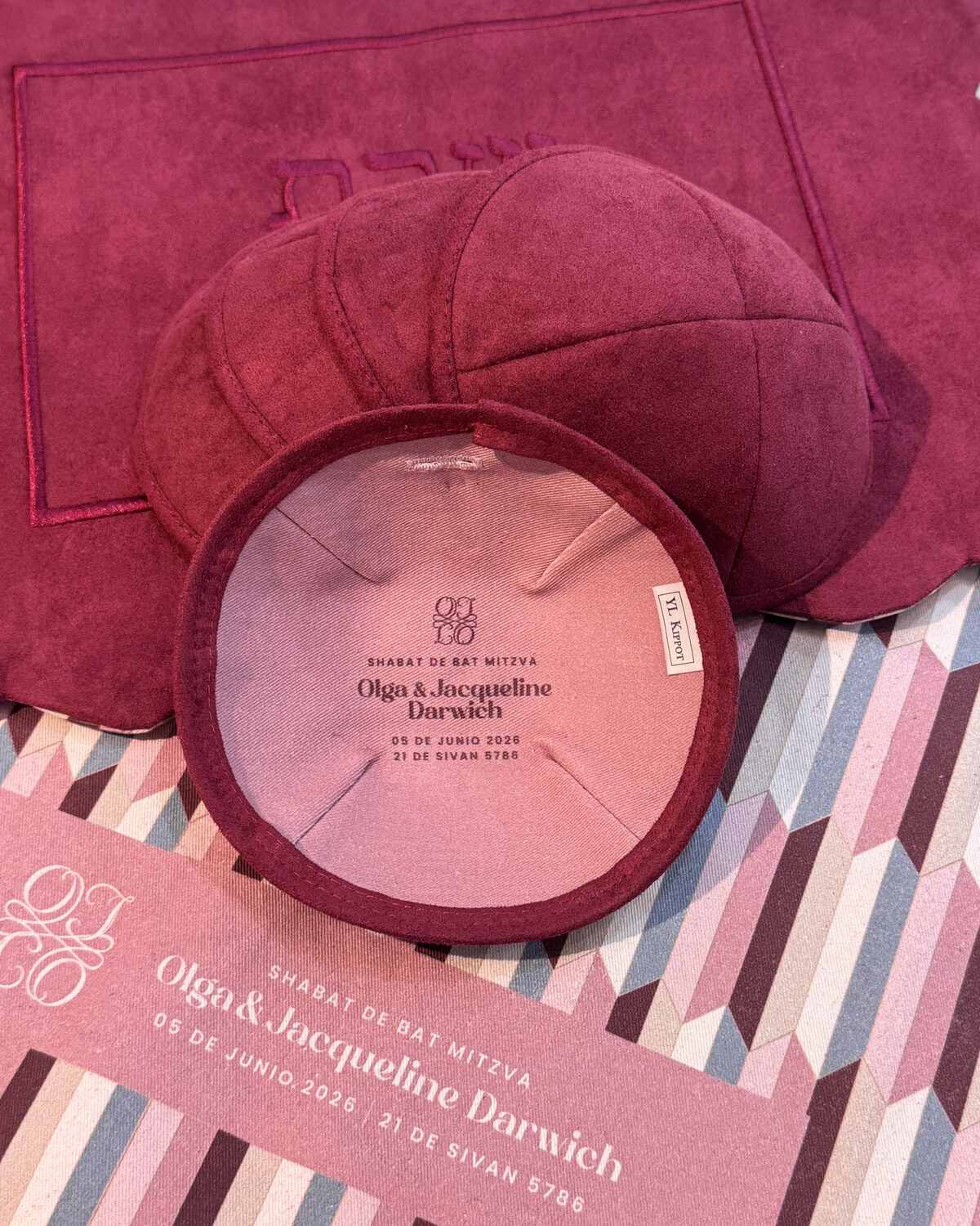 Bat mitzvah kippot color vino sobre mantelería blush con la papelería del evento